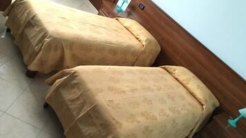 Dos camas con cubrecamas a juego, un cabecero de madera y suelo de baldosas.