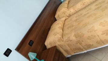 Een slaapkamer met een houten hoofdbord, een bed met beddengoed met een patroon, een nachtkastje en een nachttafel.