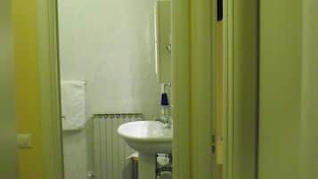 A narrow hallway leading to a bathroom with a white sink and a towel hanging on the wall.