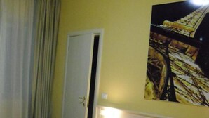 A hotel room with a bed, a nightstand, a lamp, and a painting on the wall. - Albergo Italia (Porto Tolle)