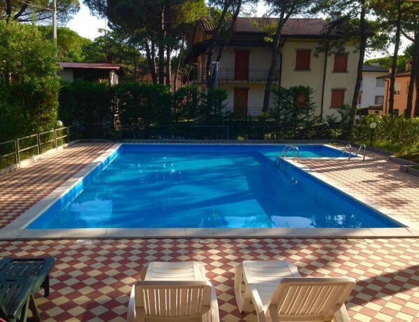 Una piscina con suelo a cuadros y sillas de descanso.