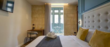 A hotel room with a large bed, a desk, and a view of the outside.