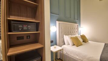 Una habitación de hotel con cama, mesita de noche, televisor integrado y minibar.