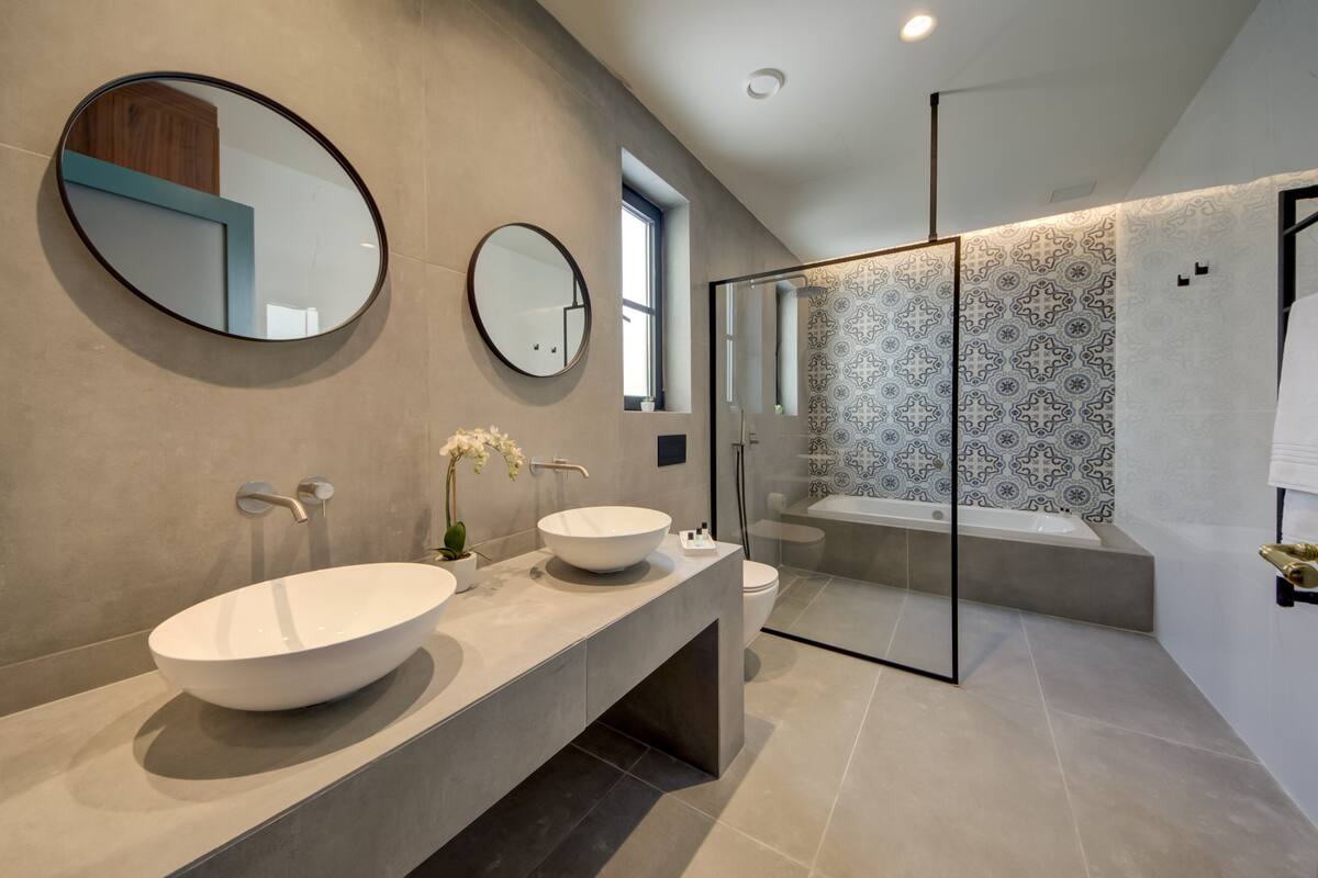 A modern bathroom with two large sinks, a toilet, and a glass-enclosed shower area.