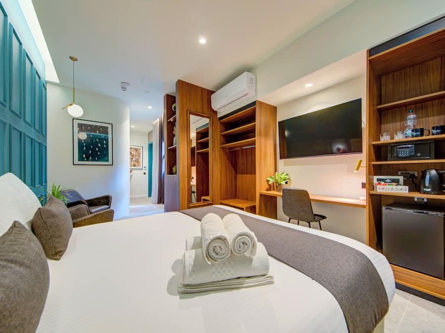 Habitación de hotel con cama, escritorio, armario y kitchenette.