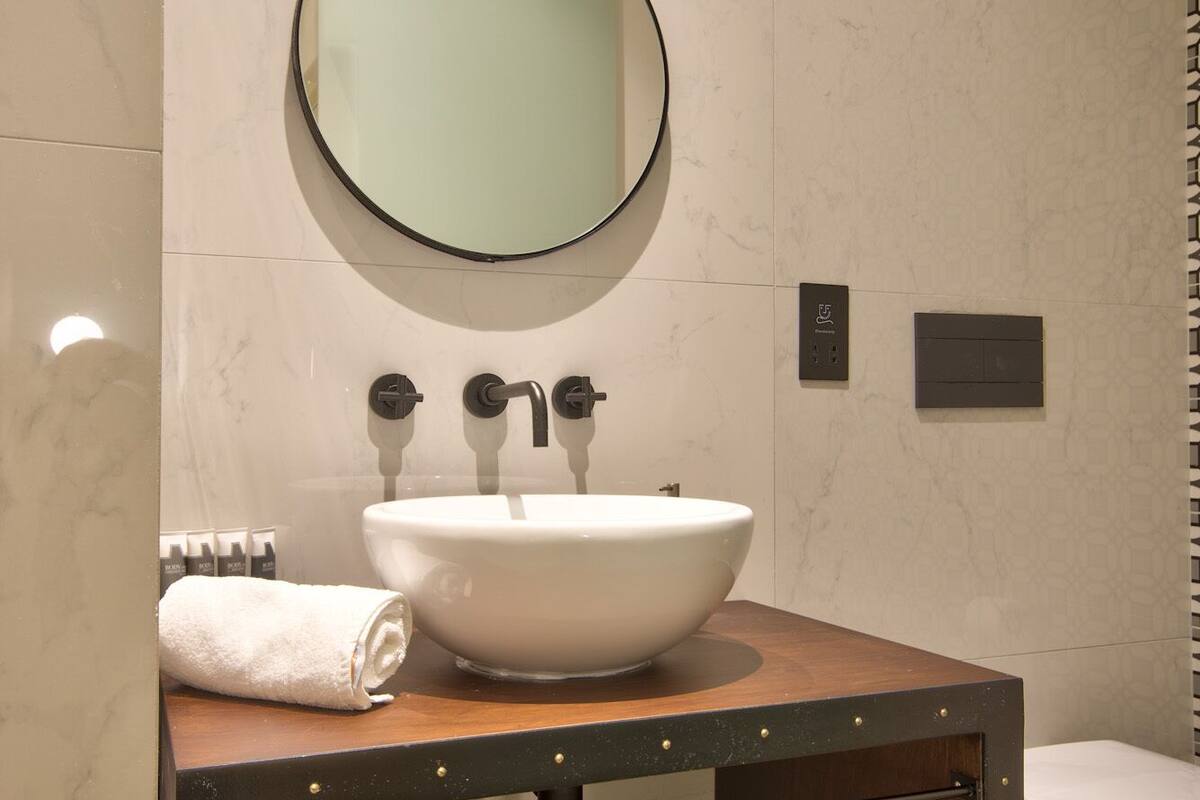 A bathroom with a round mirror, a white sink, and a towel rack.