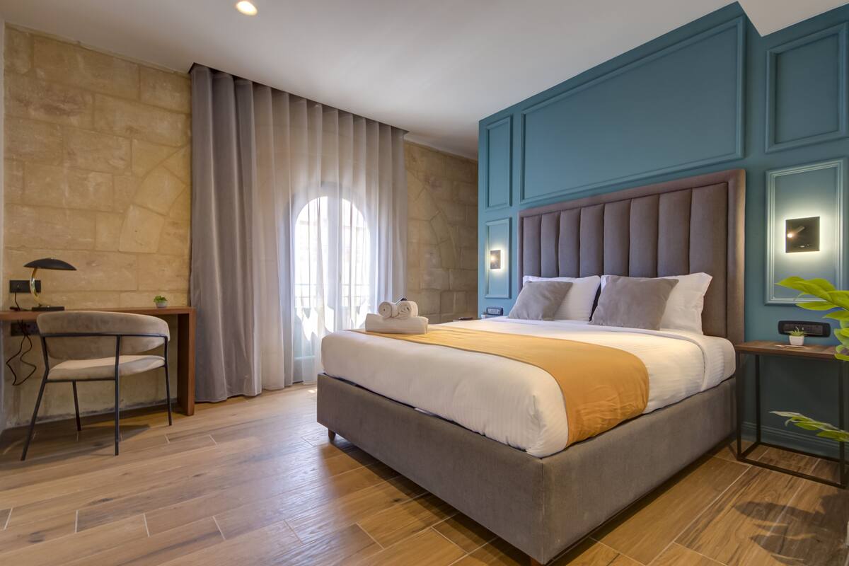 A modern hotel room with a large bed, a desk, and a chair.