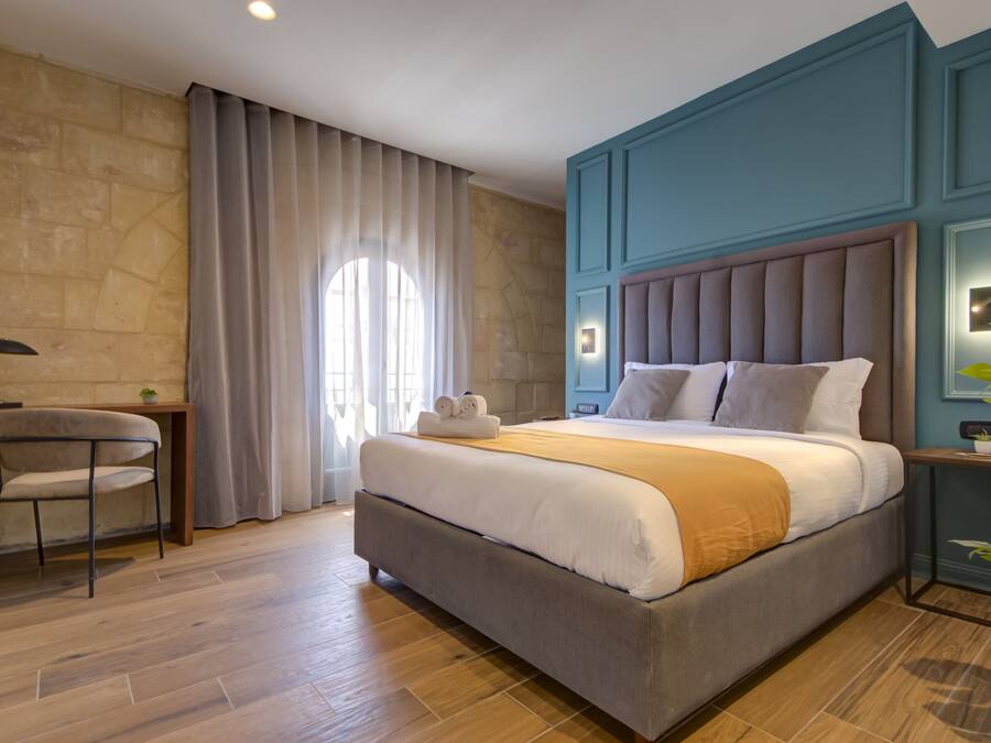 Una habitación de hotel moderna con una cama grande, un escritorio y una silla.