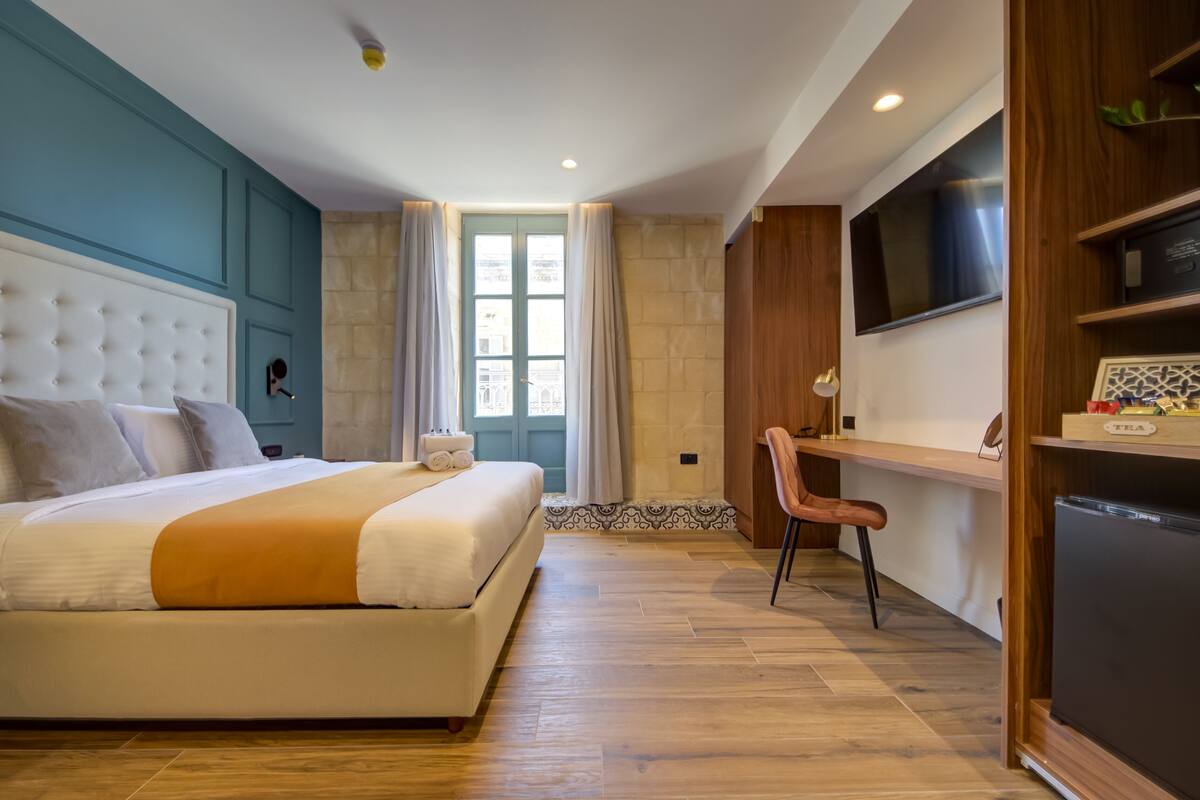 A bedroom with a bed, a desk, and a TV.