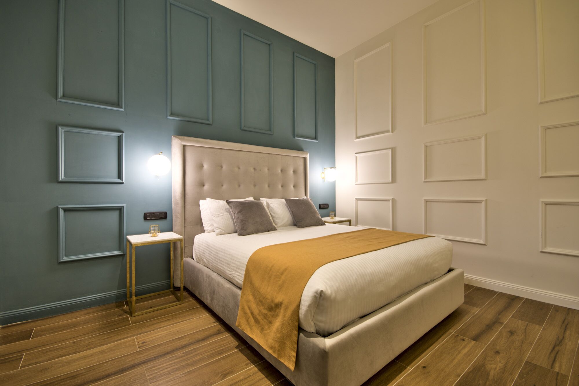 Un dormitorio con una cama grande, una mesita de noche y una lámpara fijada a la pared.