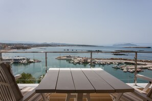 A terrace with a table and chairs overlooking a marina with boats and a distant cityscape. - Sea View Balcony, Steps from Beach and Old Town (Chania)