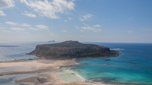 Eine Küstenlandschaft mit einer markanten Felseninsel, klarem türkisblauem Wasser und einem Sandstrand.