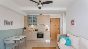 Eine moderne Küche mit Essbereich, einer Couch mit Zierkissen und einem Deckenventilator.