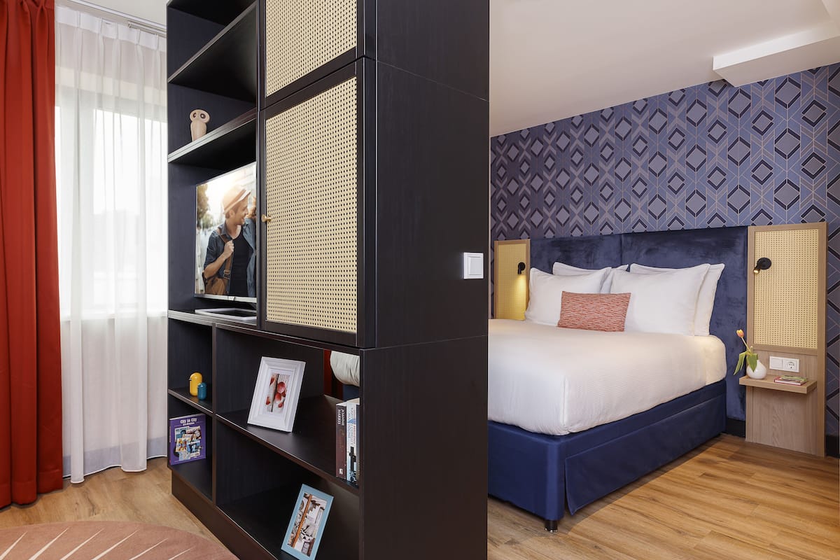 Une chambre moderne avec un grand lit, une bibliothèque et une fenêtre avec des rideaux.