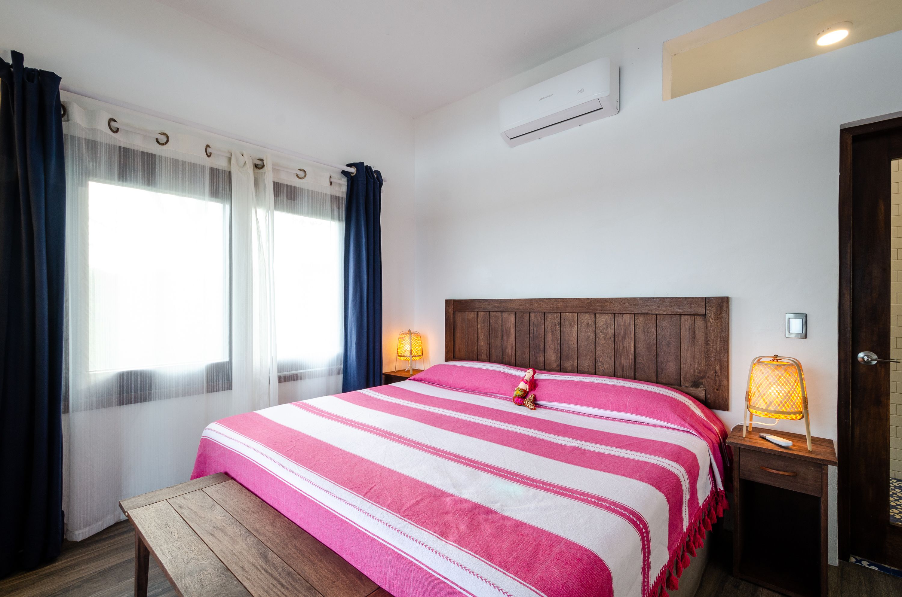 A hotel room with a bed, a nightstand, a lamp, and a window with curtains.
