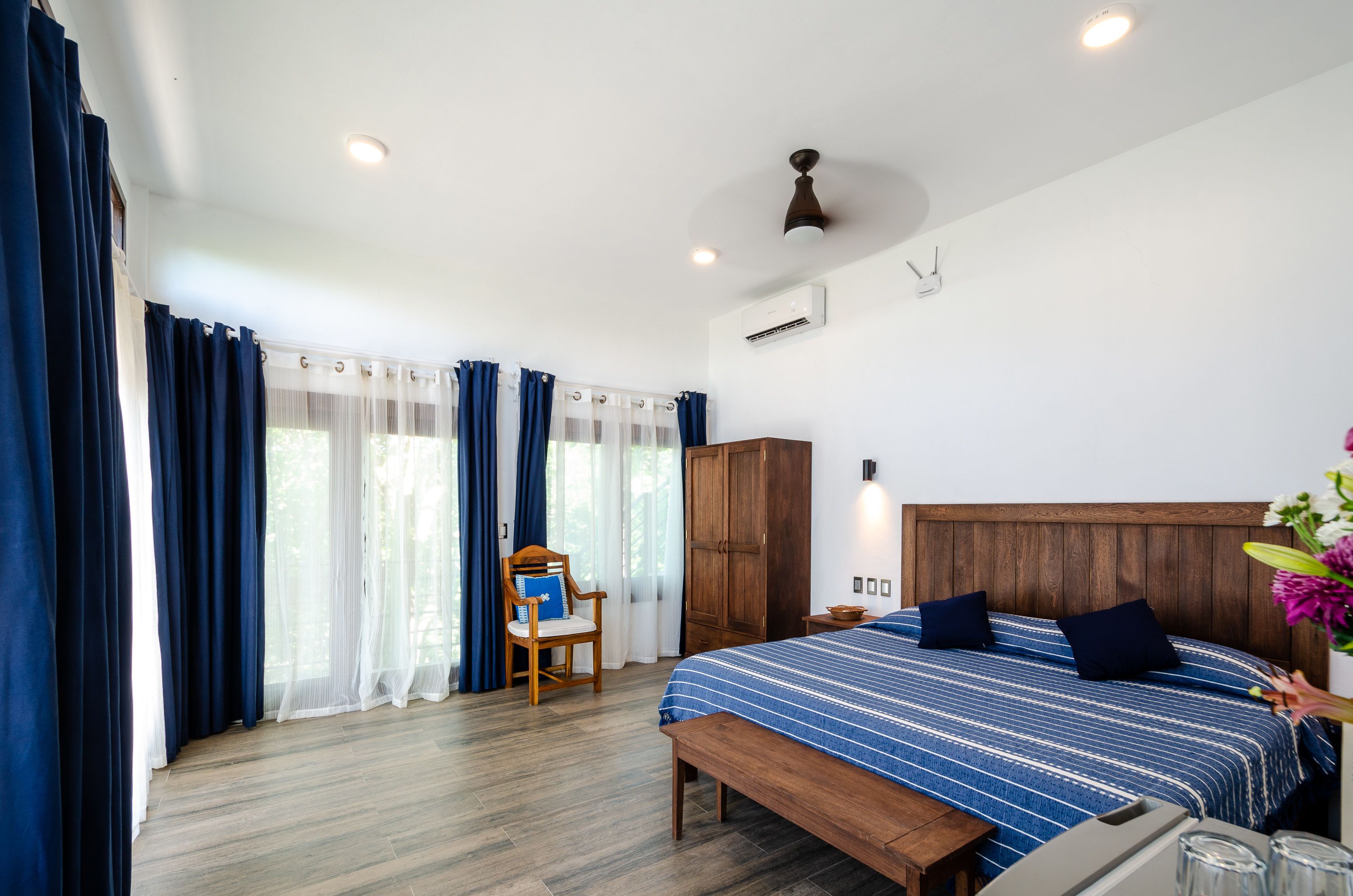 A bedroom with a wooden bed, a bench, a chair, and a bedside table.