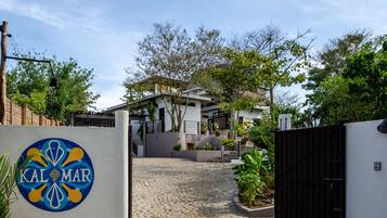 Una casa moderna con camino de entrada adoquinado, acceso mediante portón y un logotipo en la pared.