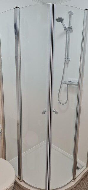 A glass-enclosed shower with a handheld showerhead and a fixed showerhead. - Harbour Bridge Camps Bar (Wick)