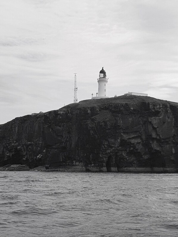 Un faro en un promontorio rocoso con vistas despejadas al agua circundante.
