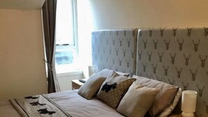 Habitació d'hotel amb llit, una taula de nit, una làmpada i una finestra amb cortines.