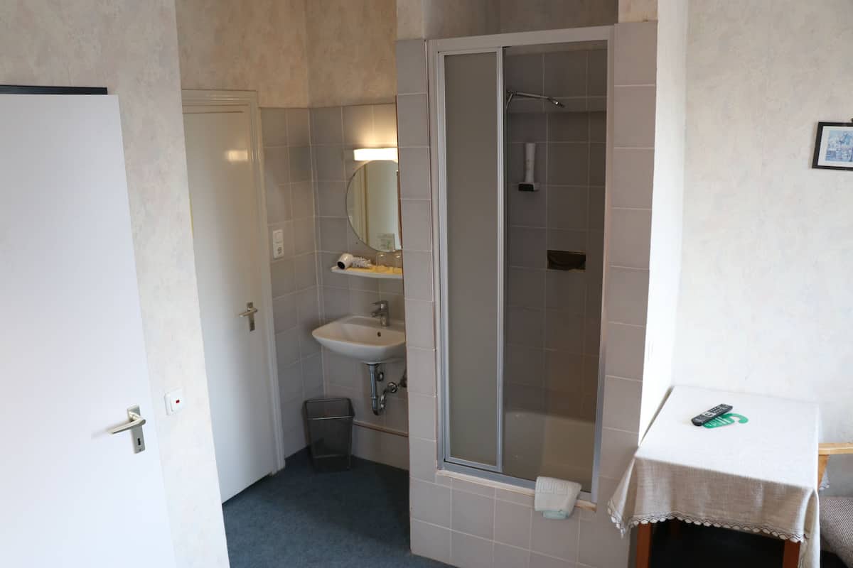 Un baño con ducha, lavamanos y espejo.