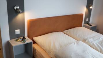 A double bed with a wooden headboard, two bedside tables, and a nightstand with a lamp.
