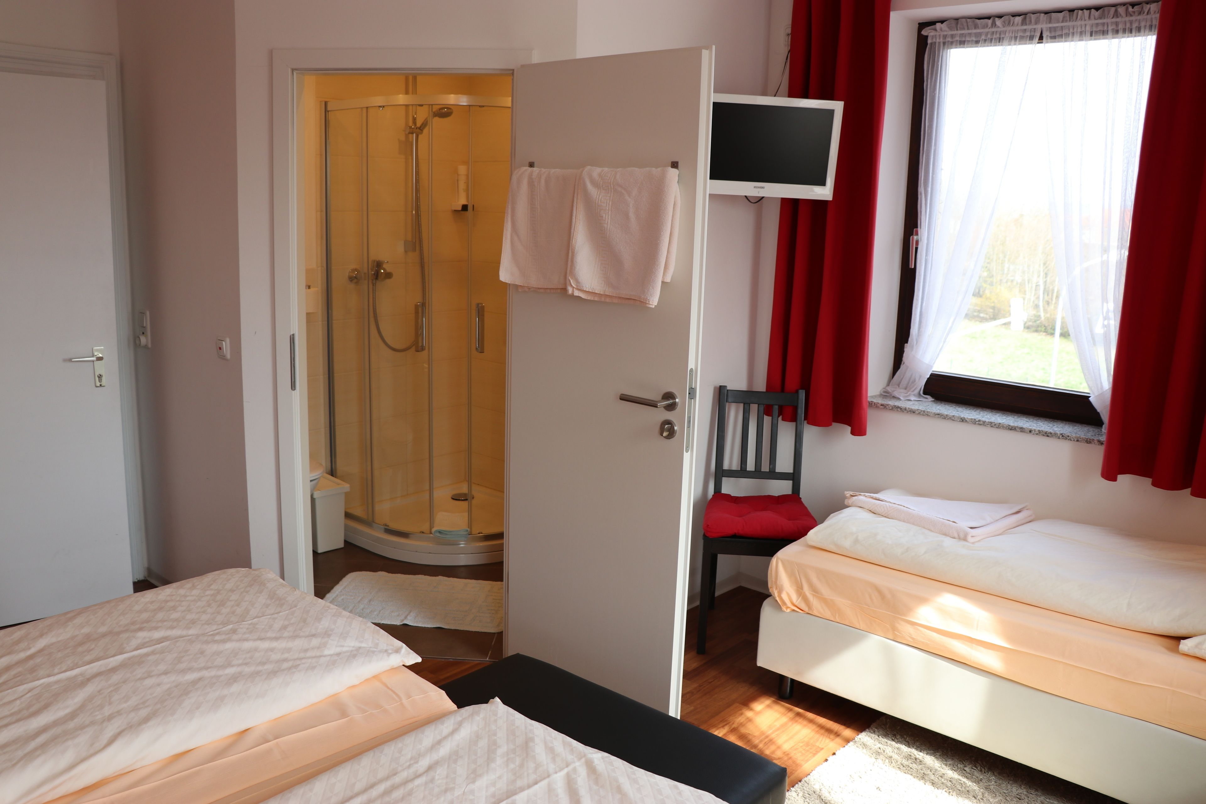 Een hotelkamer met twee bedden, een douche, een televisie en een raam met gordijnen.