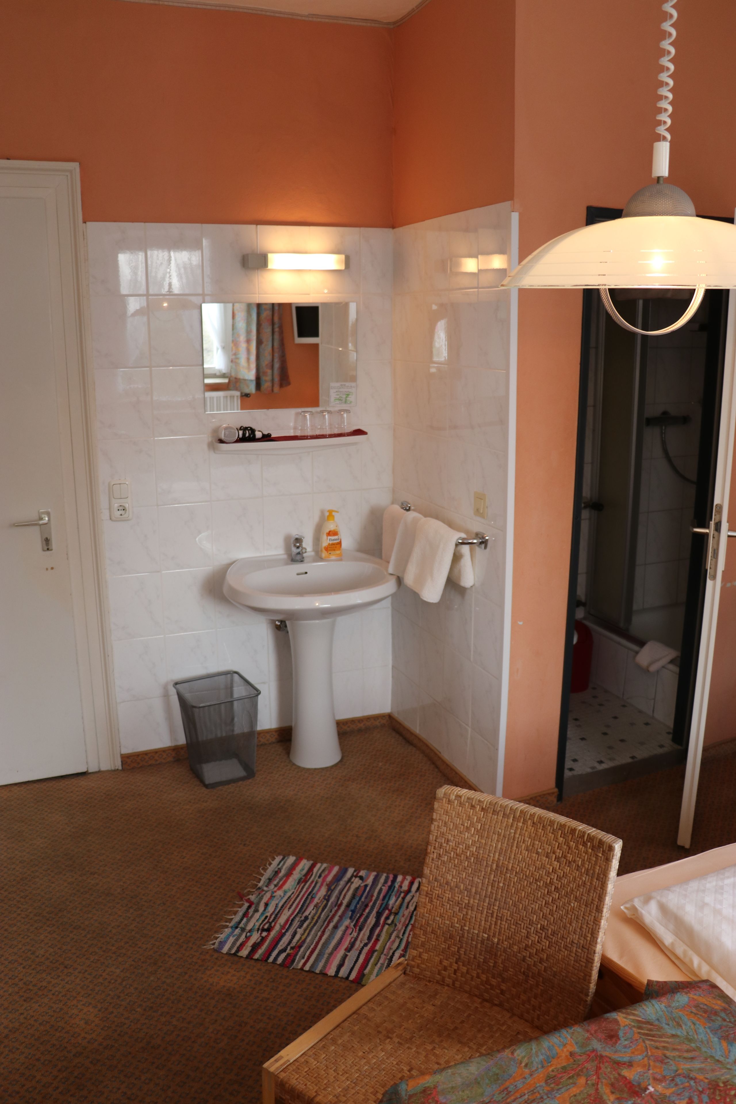 Une salle de bain équipée d’un lavabo, d’un miroir, d’un porte-serviettes et d’une douche.