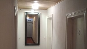 Un pasillo estrecho con techo de madera, un espejo en la pared izquierda y suelo cubierto de alfombra.