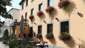 Un hotel con terraza al aire libre, jardineras florales en la fachada y un letrero que dice 'Gisippin Post Hotel-Restaurant'.