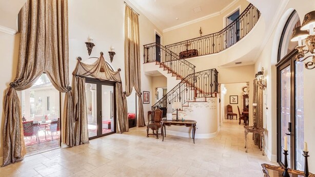 A spacious foyer with a grand staircase, a seating area, and a view to the outside. - VIP Accommodations (Hollywood)