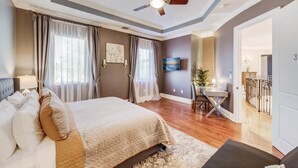 A bedroom with a bed, a desk, a chair, a ceiling fan, and a view of a balcony. - VIP Accommodations (Hollywood)