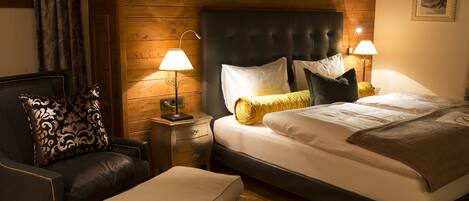 A cozy bedroom with a large bed, a chair, and a nightstand with lamps.