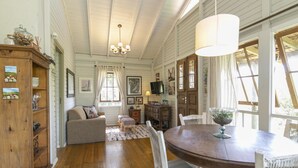 A cozy room with a wooden dining table, white chairs, a sofa, and a wooden cabinet. - Vieja Hacienda (Imbituba)