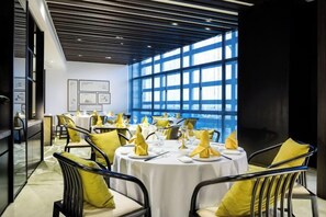 A dining area with round tables, yellow napkins, and black chairs. - Hotel Unic (NANJING)