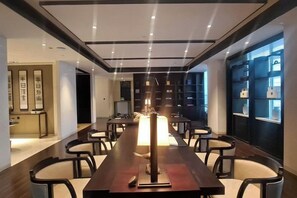 Un espace repas moderne avec une longue table, des chaises et un luminaire central.