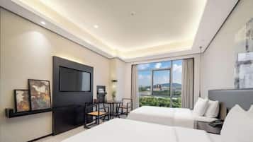 Een moderne hotelkamer met een groot bed, een bureau met stoel, een flatscreen televisie en een groot raam met uitzicht op de stad.