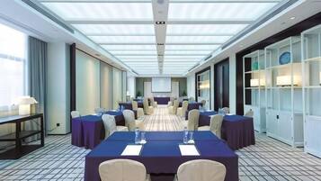 A conference room with a long table, chairs, and a projector screen.