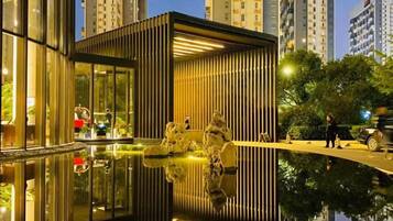 Un bâtiment moderne doté d’un bassin d’eau réfléchissant, entouré d’immeubles résidentiels de grande hauteur.