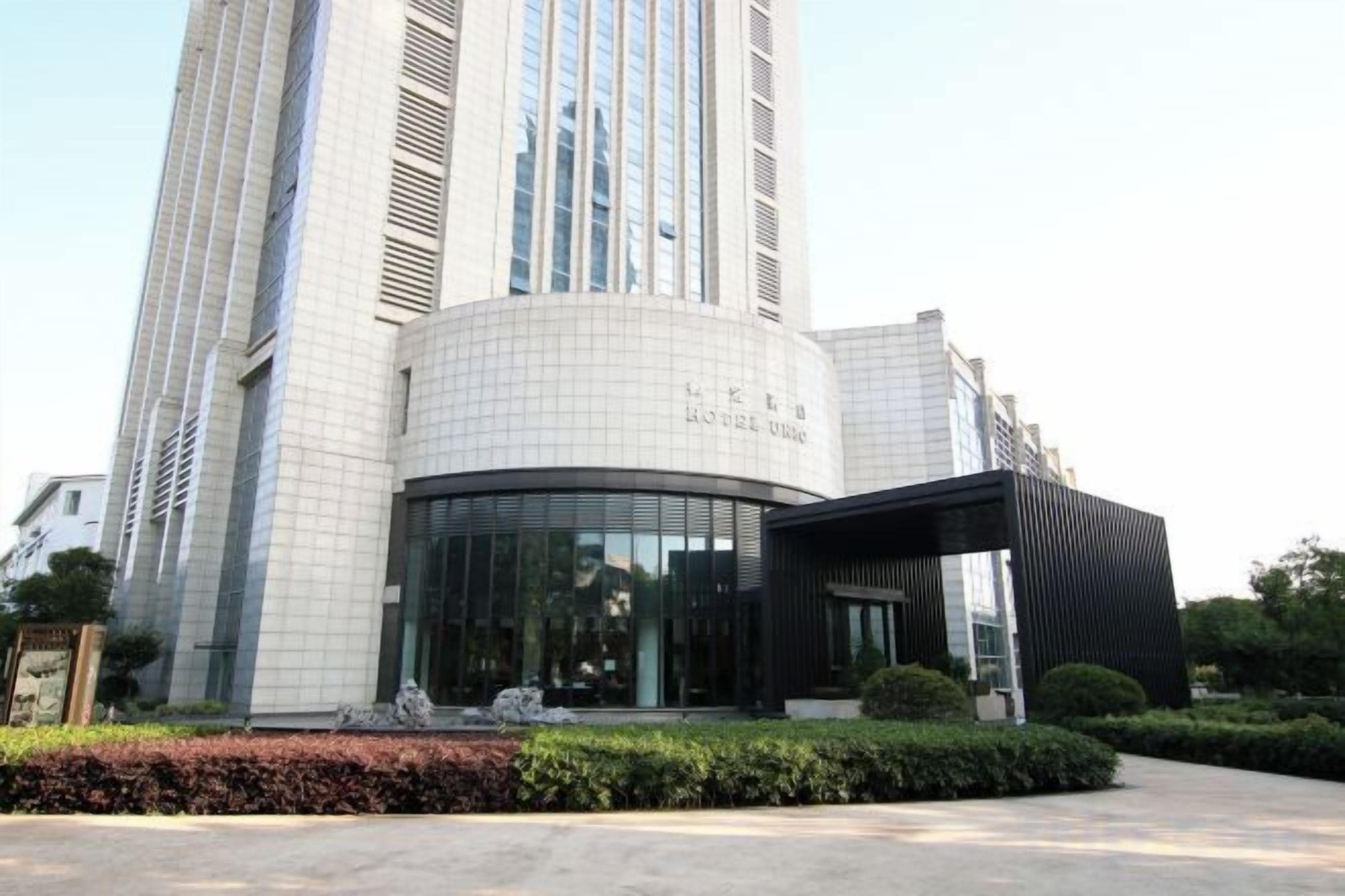 A modern building with a curved facade, large windows, and a black entrance canopy.