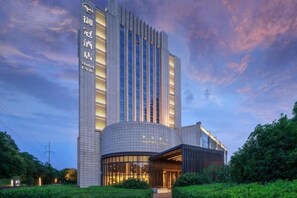 Un hôtel au design moderne, caractérisé par un bâtiment imposant aux lignes verticales et une entrée incurvée.