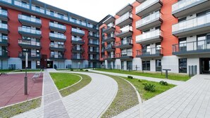 A modern apartment building with multiple balconies, a central courtyard with a curved pathway, and a red-tiled area. - CVO INN Cracow Old Town (Kraków)