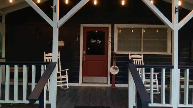 A porch with a red door, white railings, and string lights. - “Lake Life” - Boat ramp here (Broaddus)