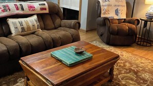 A living room with a brown leather sofa, a wooden coffee table, and a patterned rug. - “Lake Life” - Boat ramp here (Broaddus)