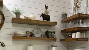 A kitchen with white cabinets, a granite countertop, and wooden shelves holding various items like a coffee maker, mugs, and decorative objects. - “Lake Life” - Boat ramp here (Broaddus)