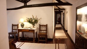 A cozy room with exposed wooden beams, a table with a vase and lamp, and a chair. - Quinta da Cumieira (Santa Marta de Penaguião)
