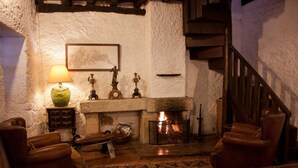 A cozy living room with a fireplace, leather armchairs, a patterned rug, and a green vase on a side table. - Quinta da Cumieira (Santa Marta de Penaguião)