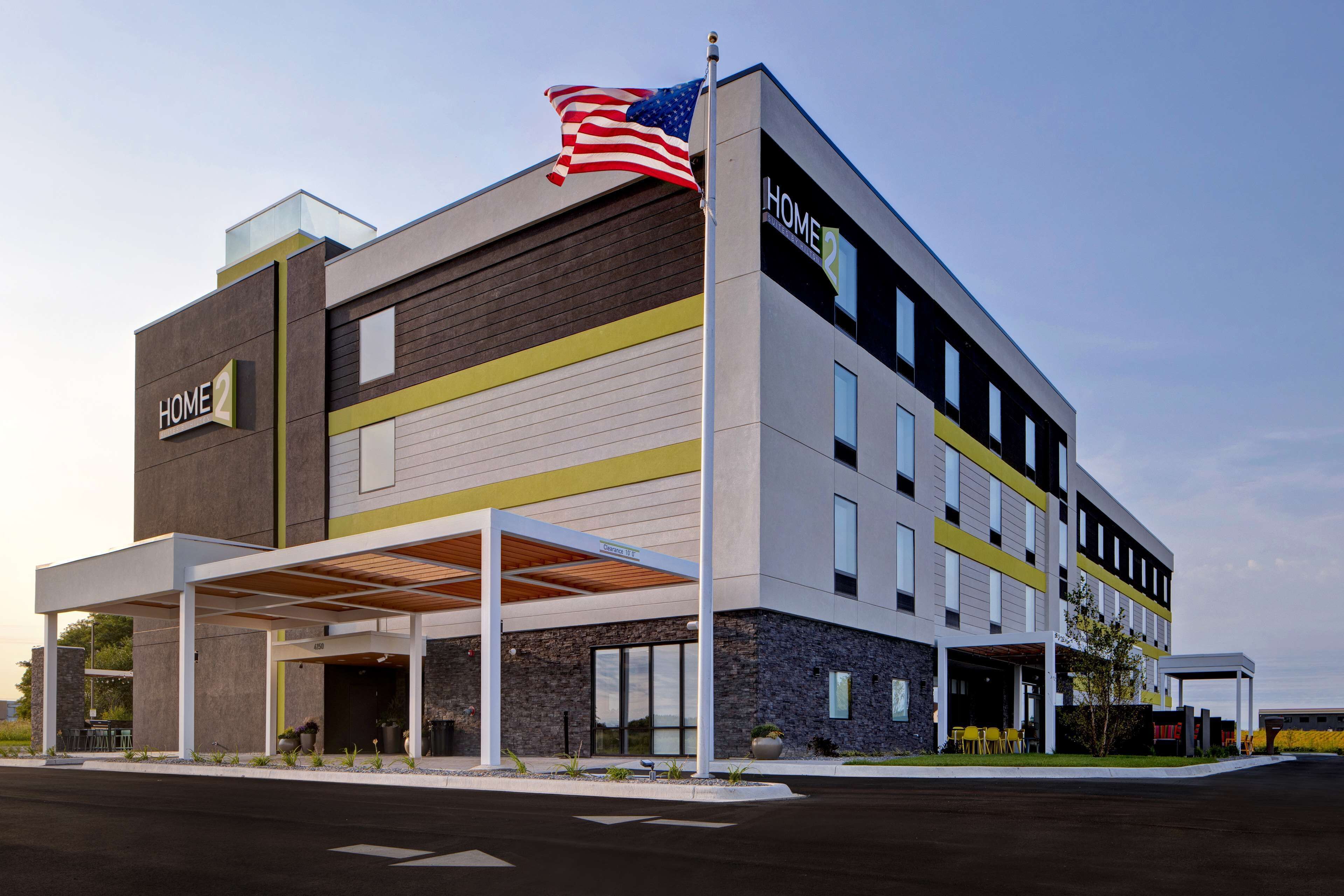 A modern hotel with a flat roof, a covered outdoor area, and a flag on top.