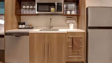 Cocina compacta con microondas integrado, refrigerador de acero inoxidable y lavavajillas.