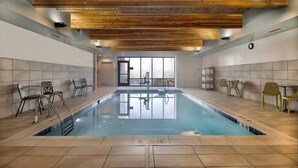 An indoor swimming pool with wooden ceiling beams, tiled walls, and a clear view of the outside through large windows. - Home2 Suites by Hilton Loves Park Rockford (Loves Park)